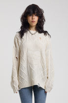 Cream oversized cable knit jumper with skull motif and distressed details, worn by model