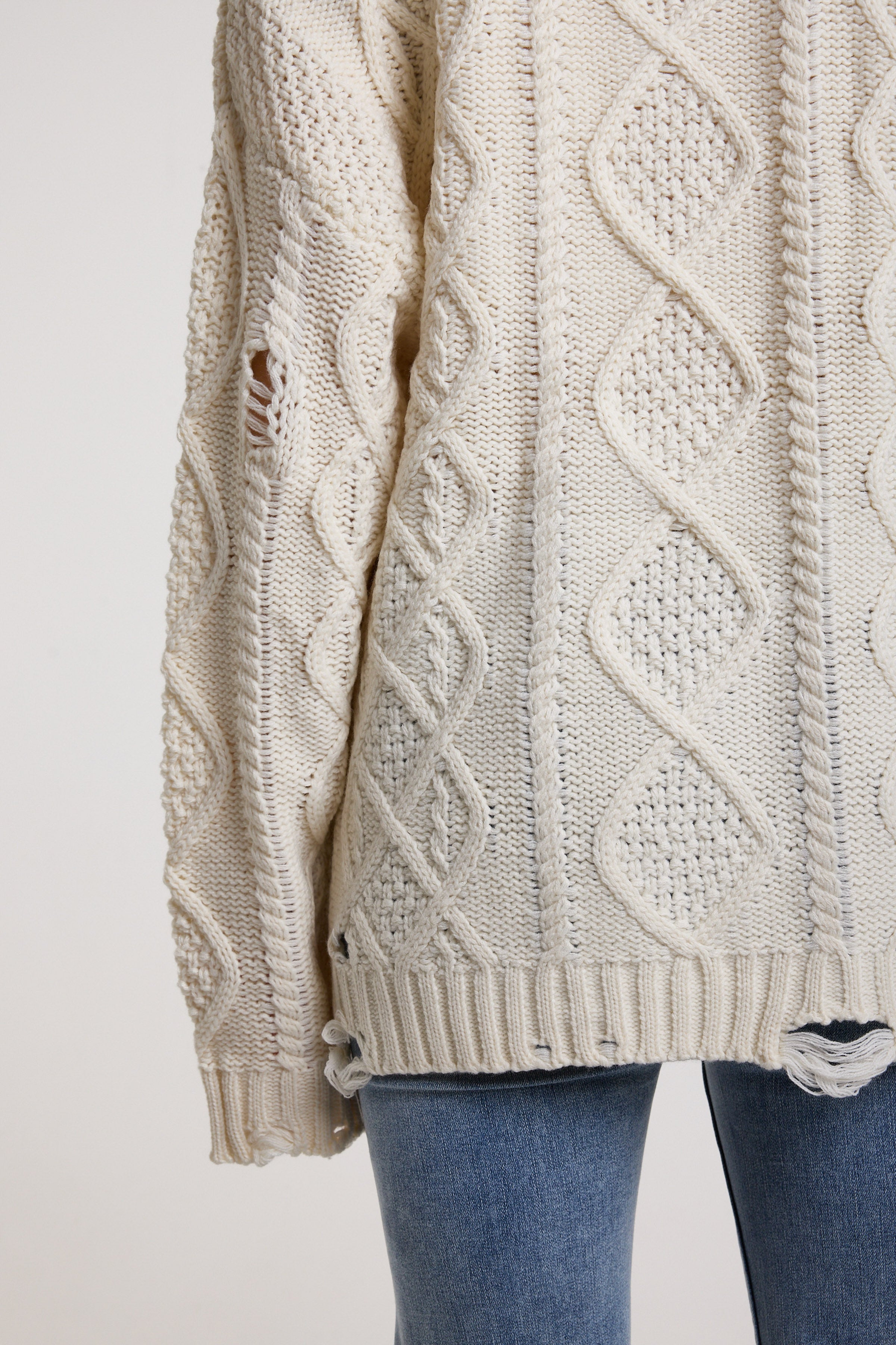 Close up of distressed details on cream oversized cable knit jumper