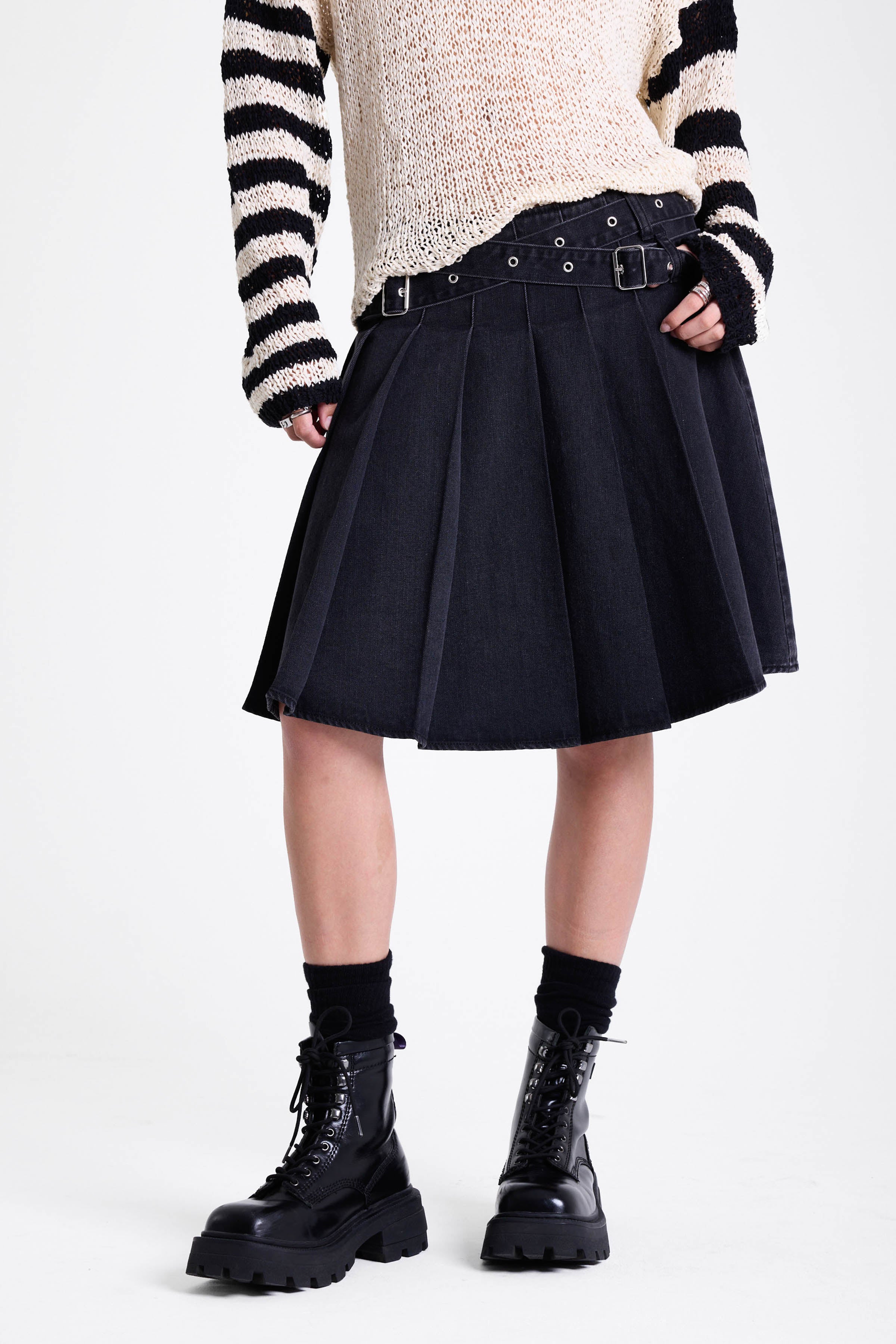 Washed denim pleated midi skirt with double eyelet crossover belt detail, worn by model
