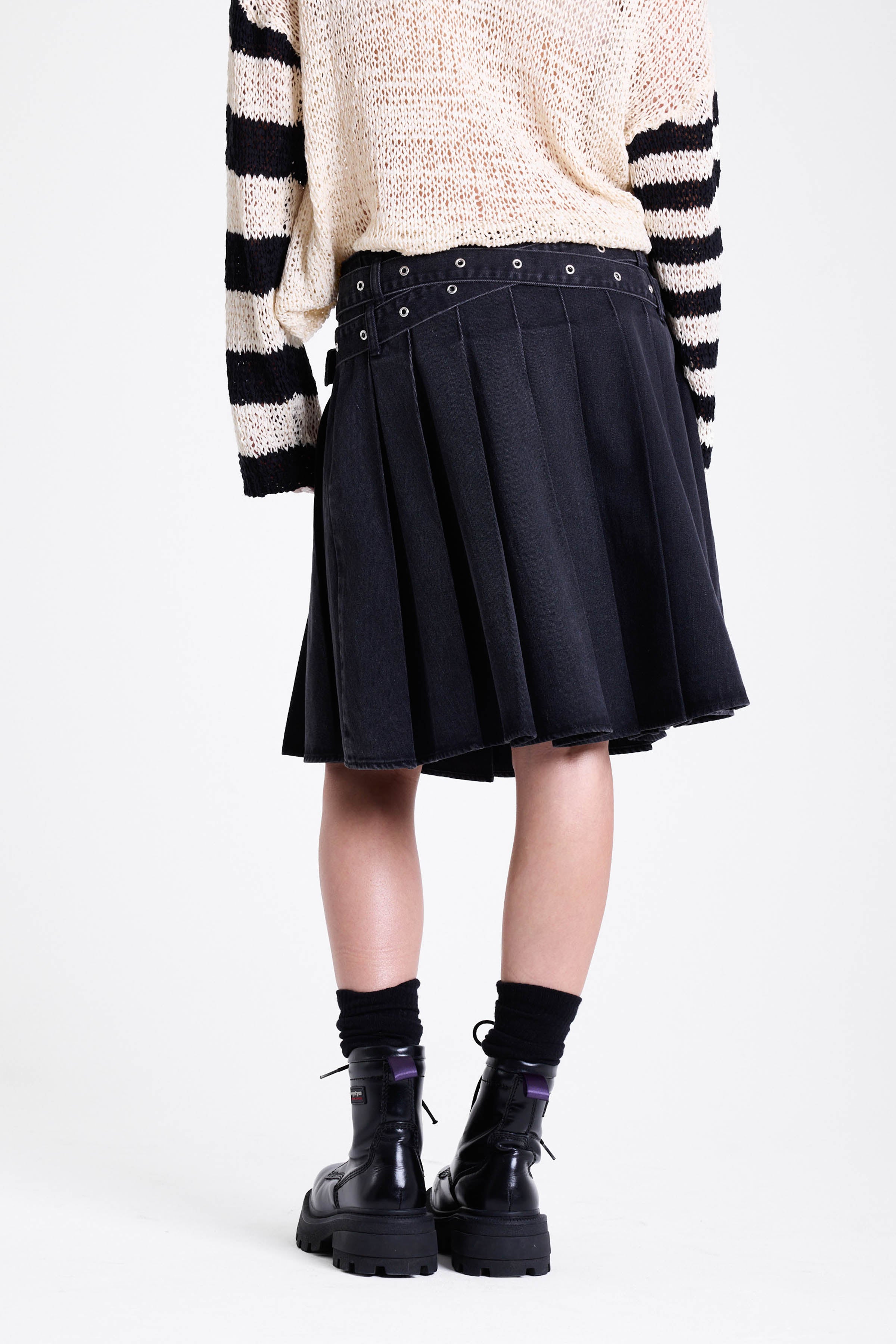Washed denim pleated midi skirt with double eyelet crossover belt detail, worn by model