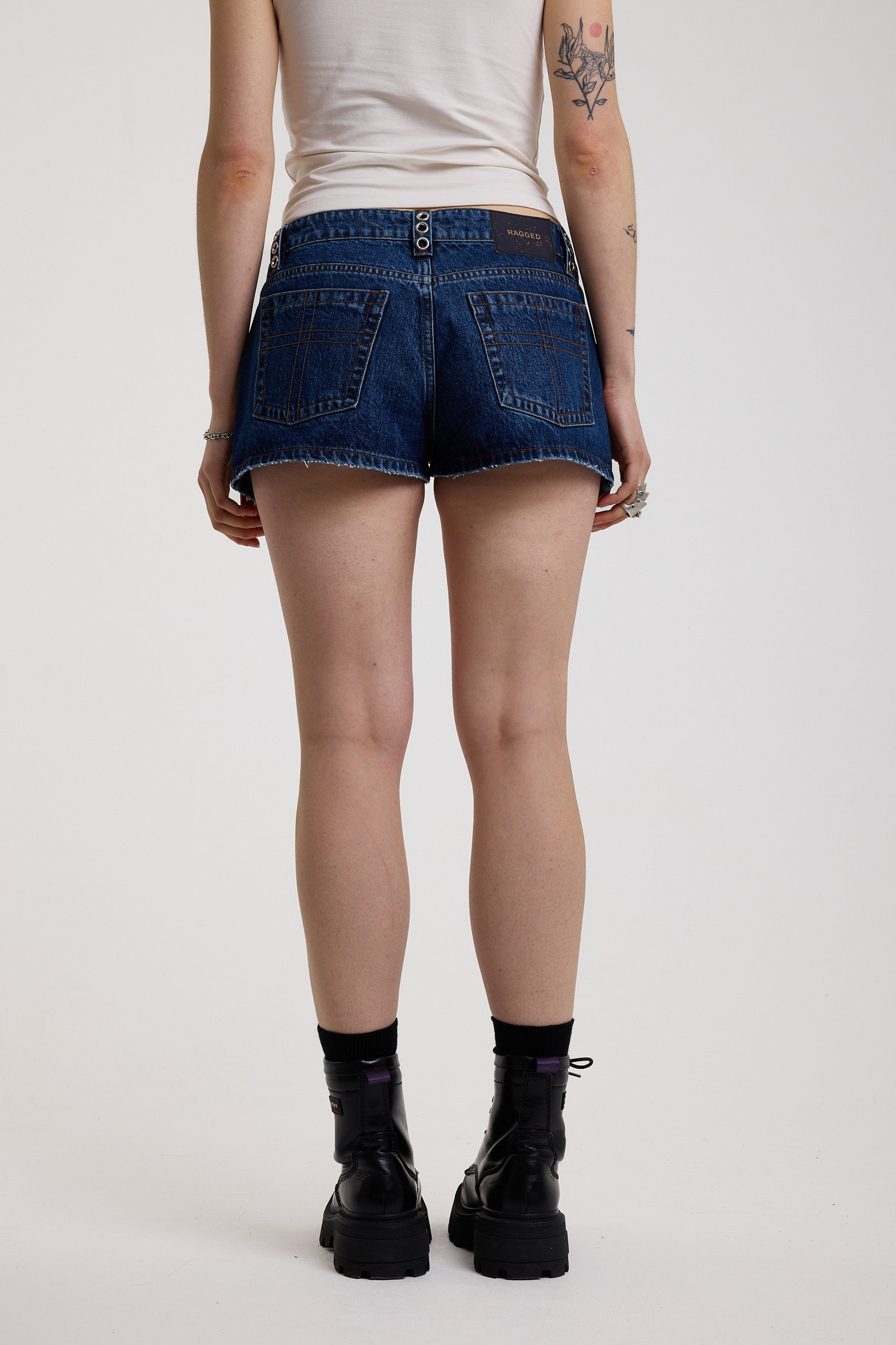 Dark rinse denim hotpants with silver eyelet grommet studs and lace up front detail, worn by model