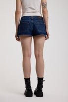 Dark rinse denim hotpants with silver eyelet grommet studs and lace up front detail, worn by model
