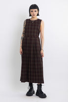 Burgundy check pinafore midi dress with pleated skirt with silver D-ring hardware, worn by model