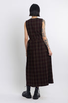 Burgundy check pinafore midi dress with pleated skirt with silver D-ring hardware, worn by model