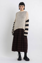 Ecru open knit jumper with asymmetric black stripe sleeves, worn by model