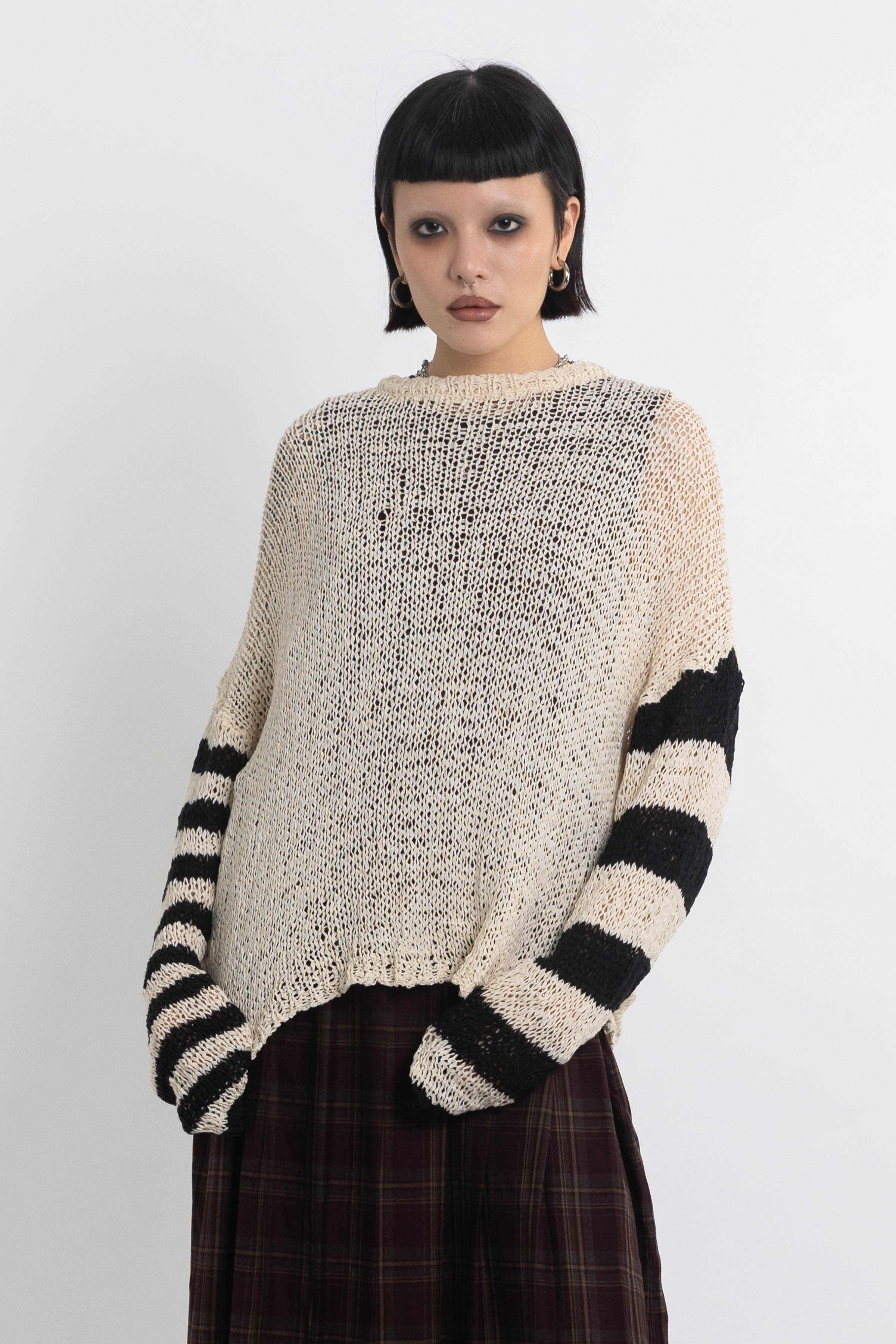 Ecru open knit jumper with asymmetric black stripe sleeves, worn by model