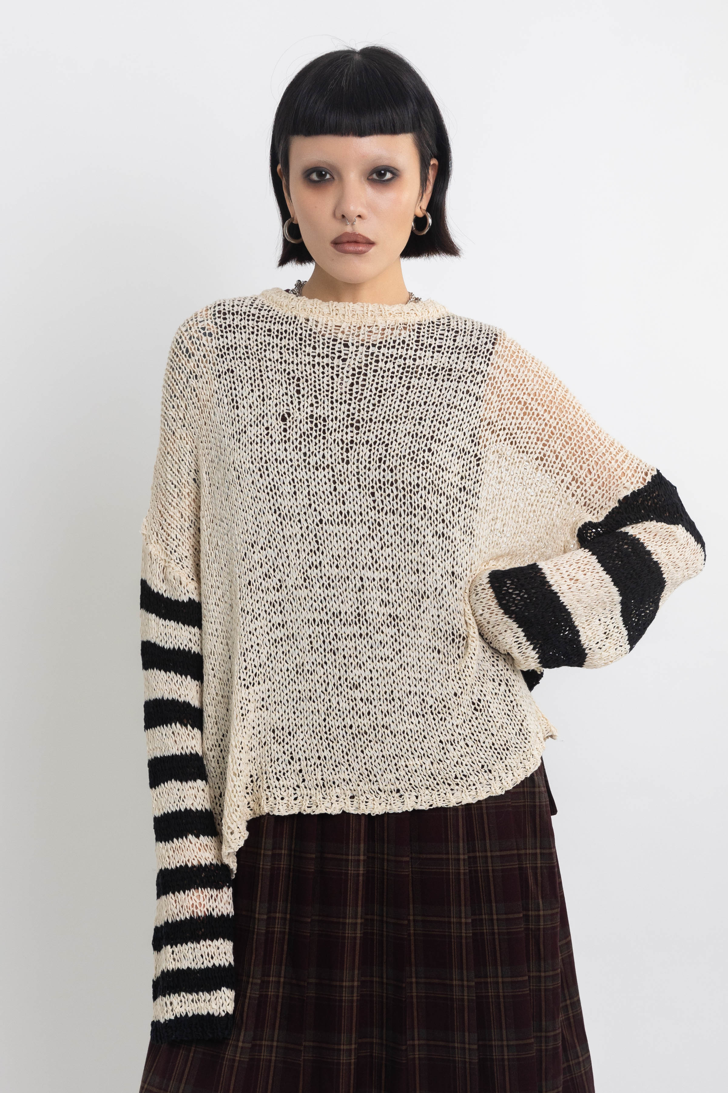 Ecru open knit jumper with asymmetric black stripe sleeves, worn by model