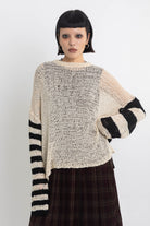 Ecru open knit jumper with asymmetric black stripe sleeves, worn by model