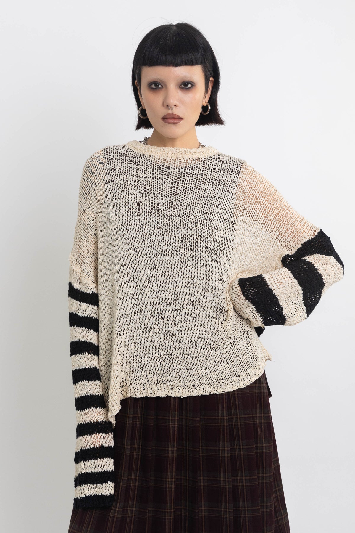 Ecru open knit jumper with asymmetric black stripe sleeves, worn by model