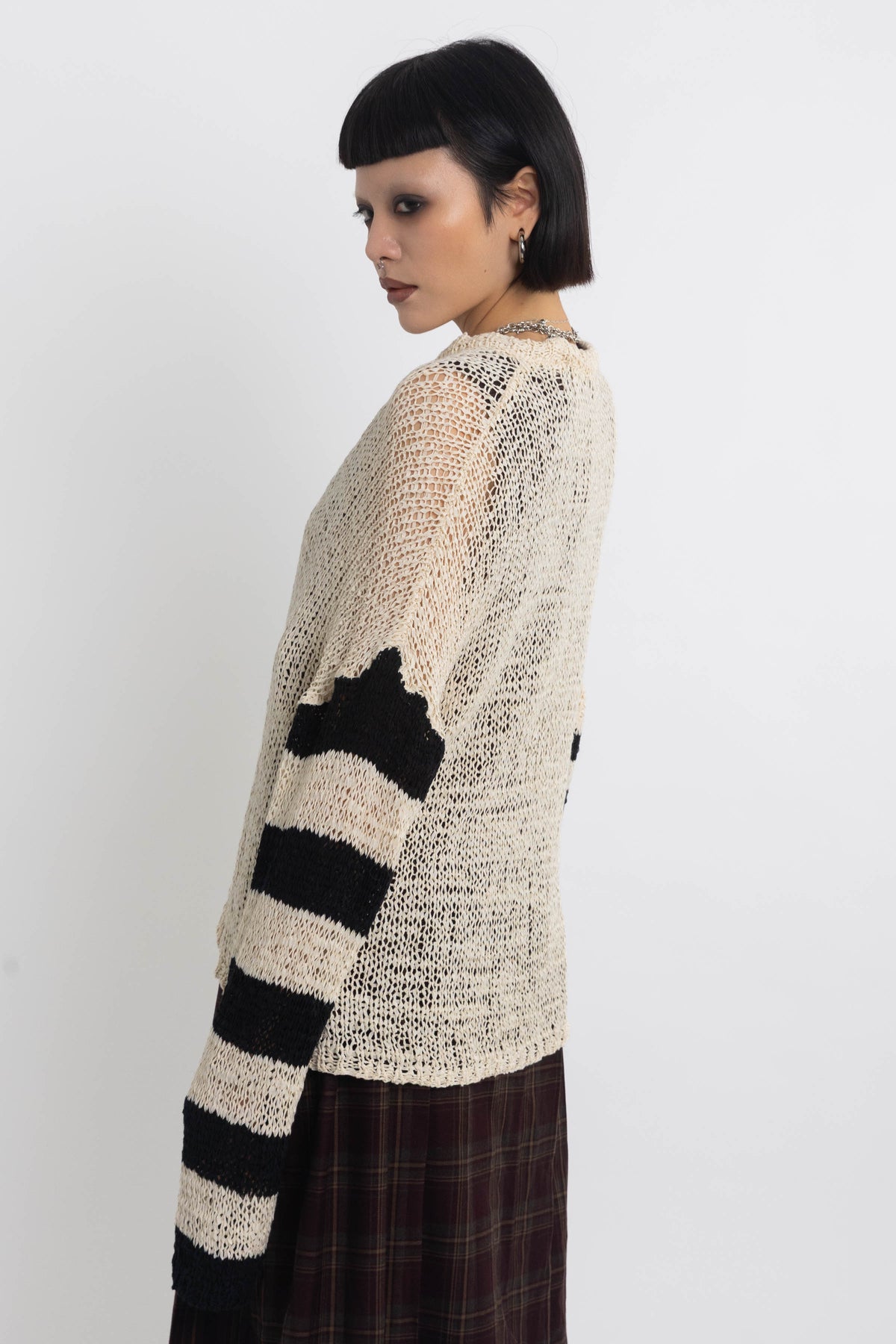 Ecru open knit jumper with asymmetric black stripe sleeves, worn by model