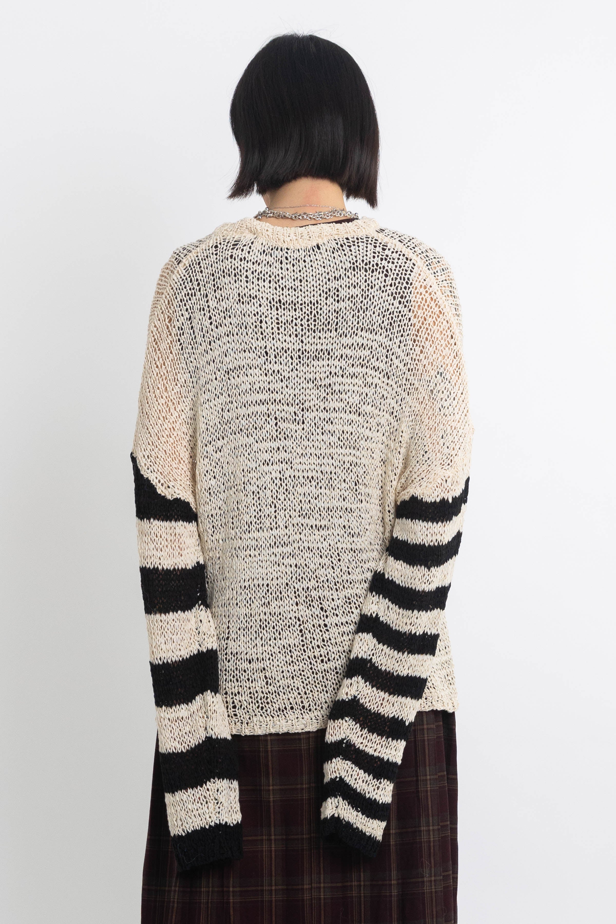 Ecru open knit jumper with asymmetric black stripe sleeves, worn by model