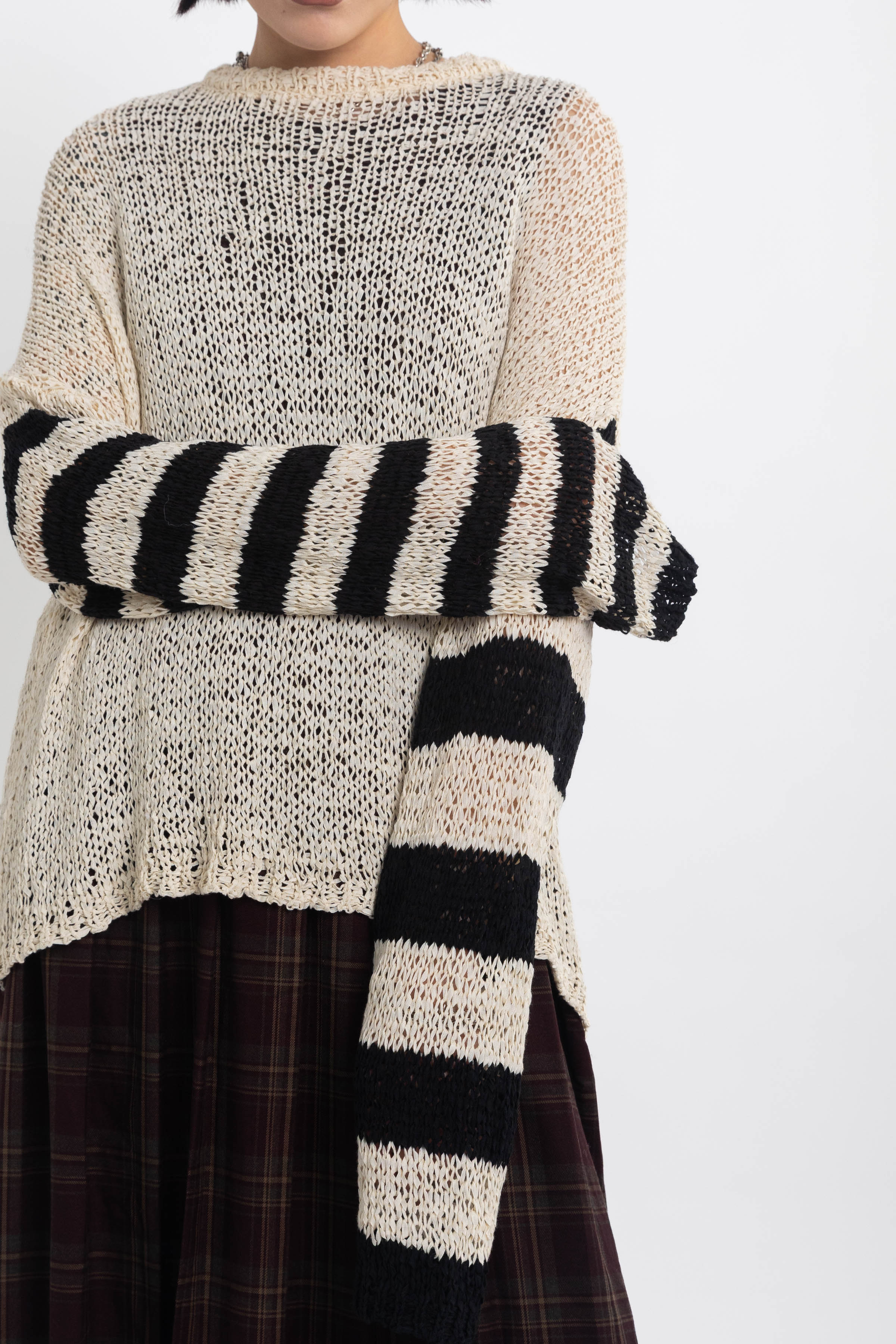 Ecru open knit jumper with asymmetric black stripe sleeves, worn by model