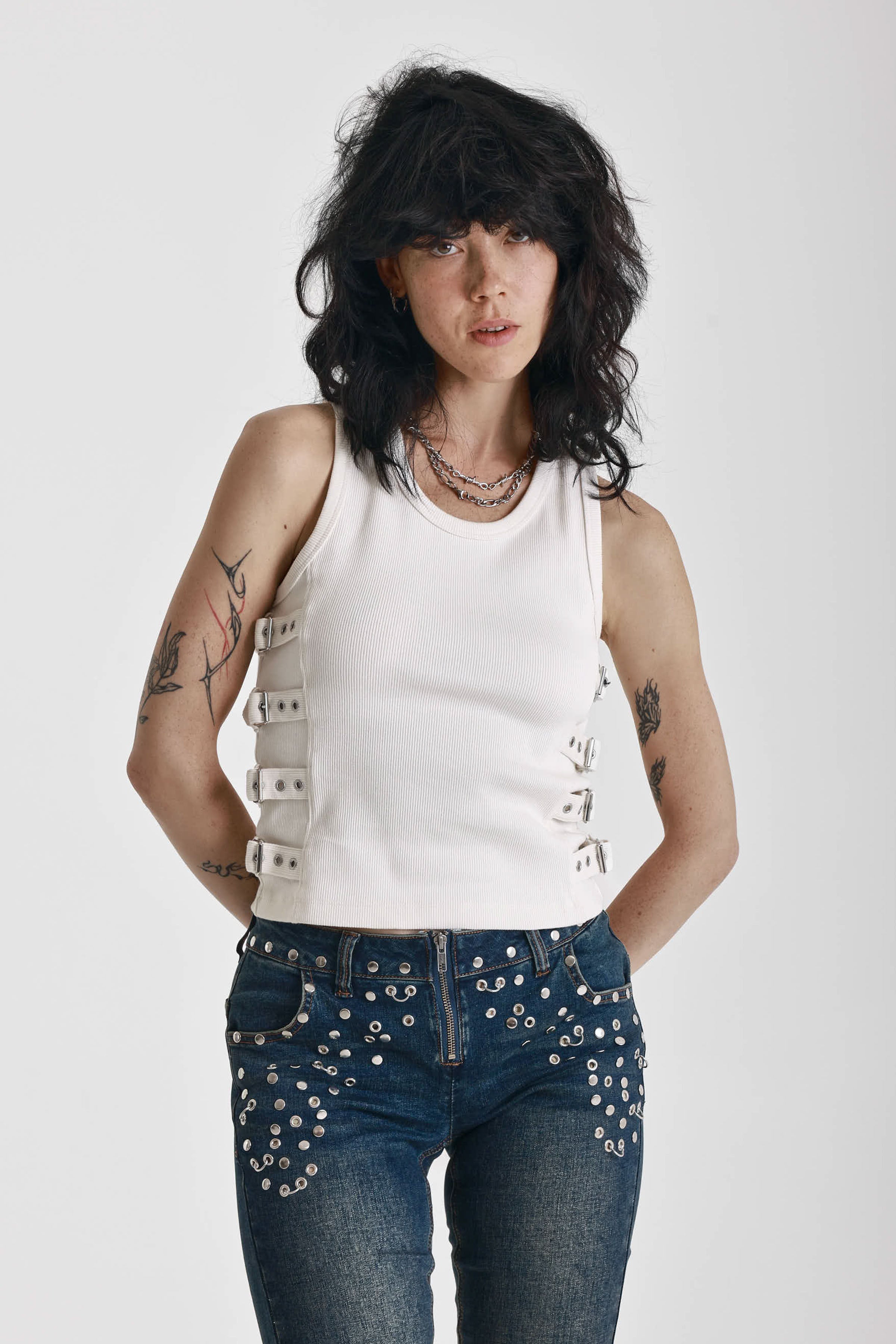 Ecru ribbed tank top with eyelet and buckle strap detail, worn by model