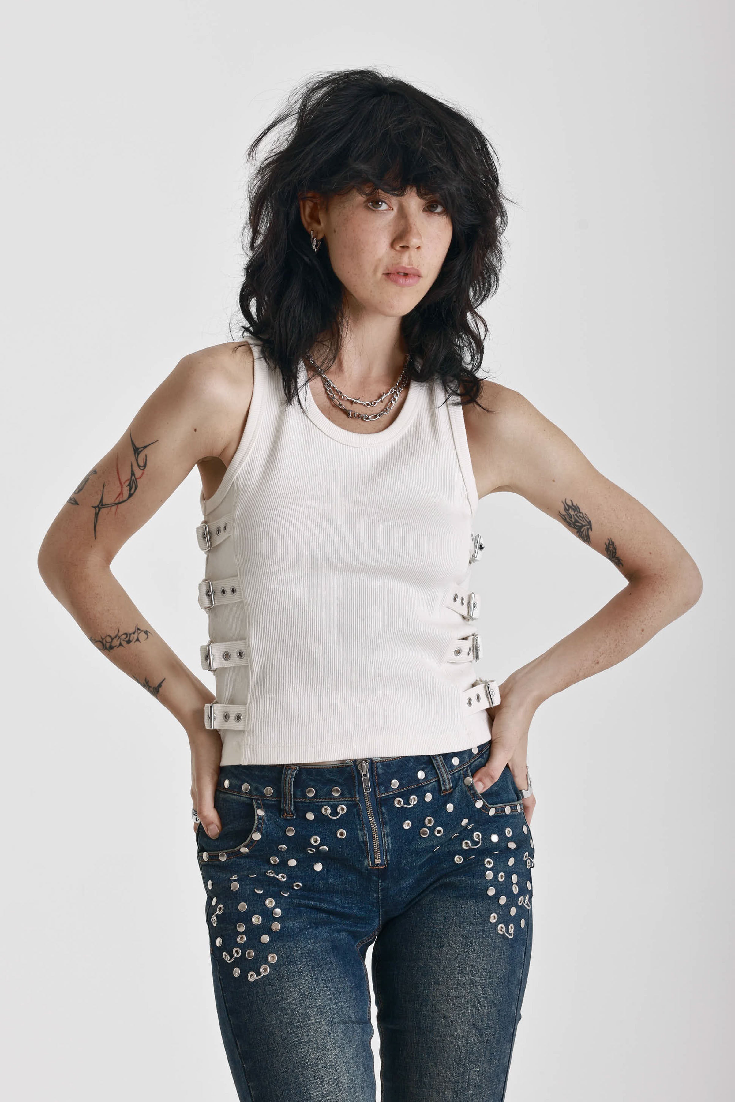 Ecru ribbed tank top with eyelet and buckle strap detail, worn by model