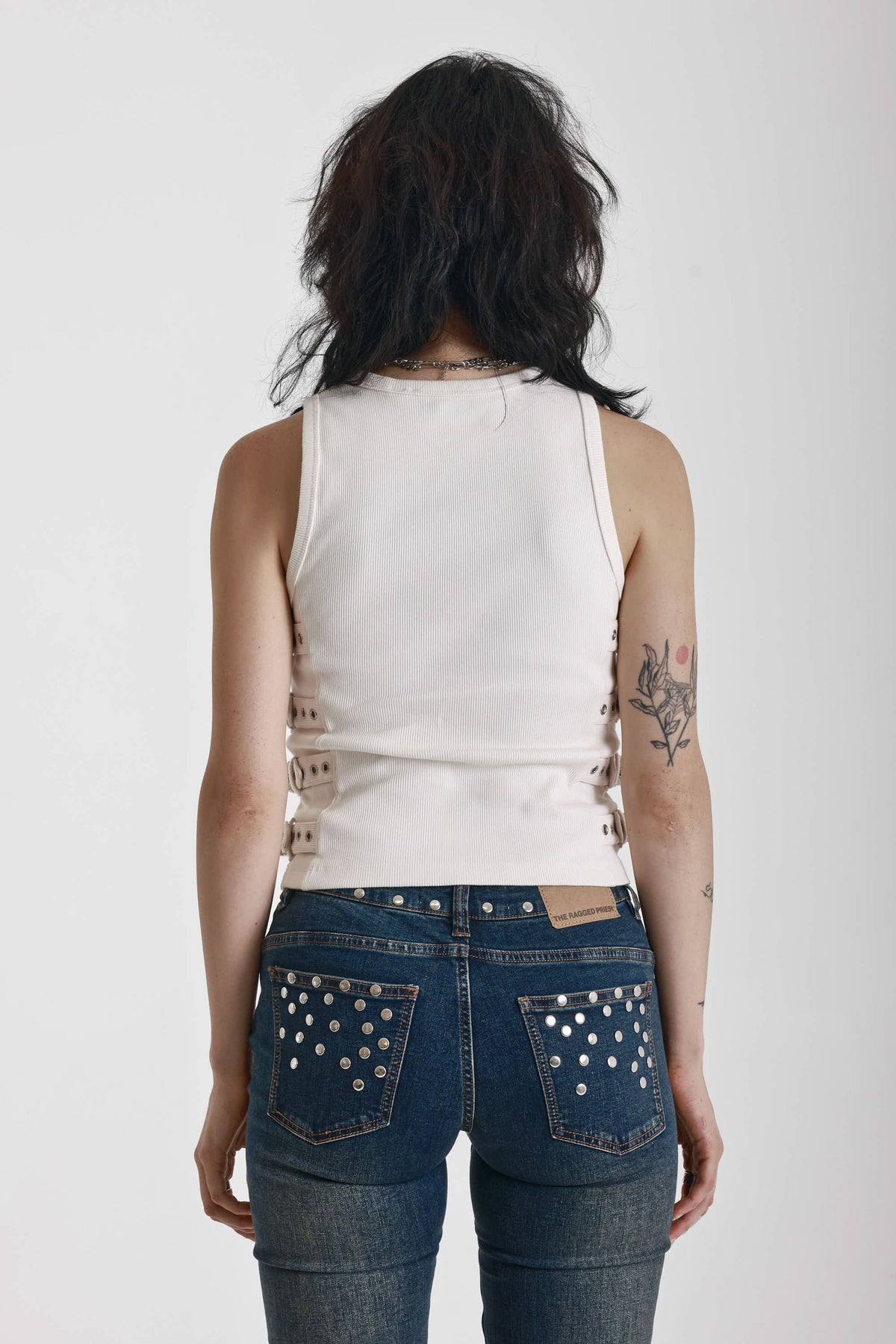 Ecru ribbed tank top with eyelet and buckle strap detail, worn by model