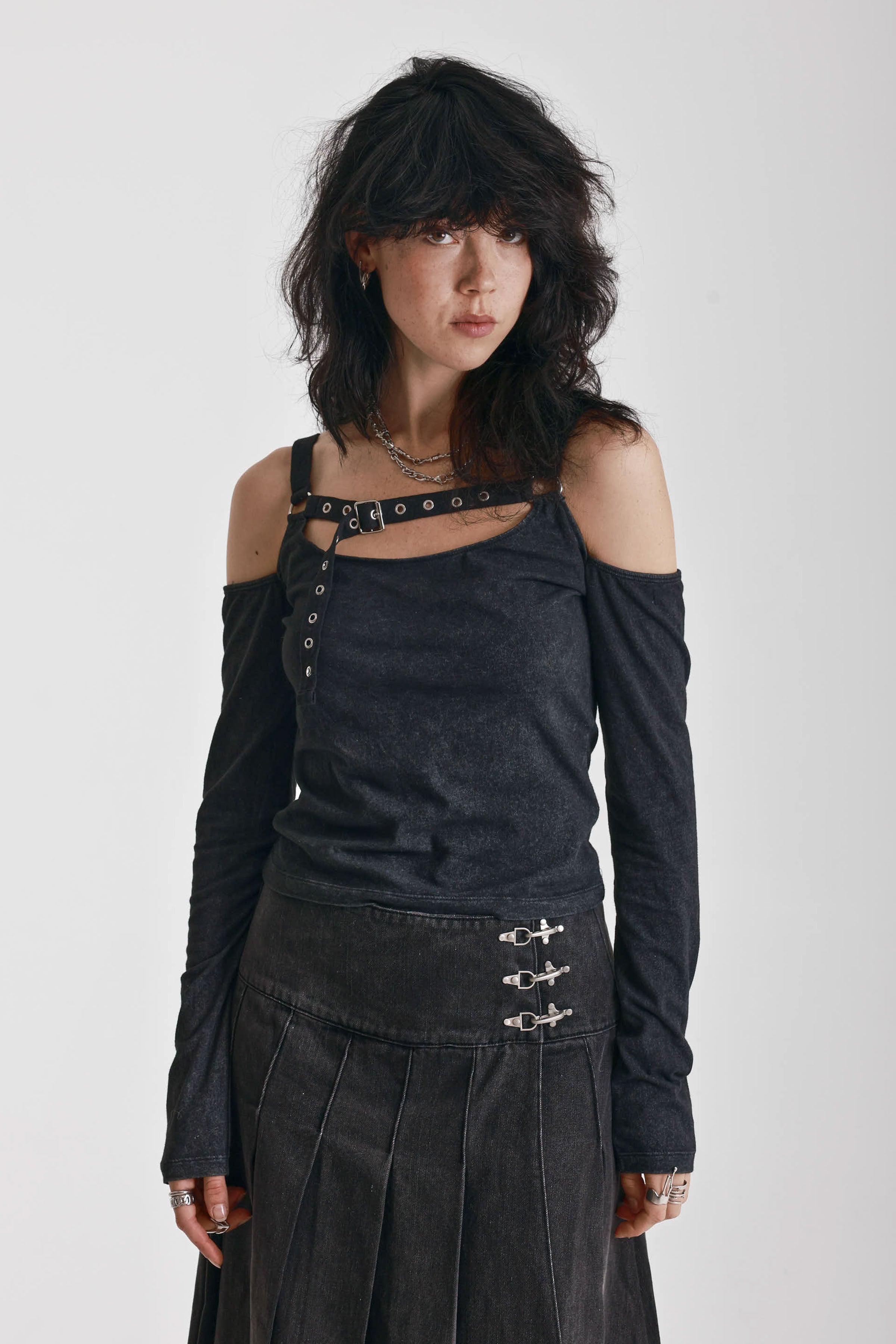 Washed black long-sleeve cold-shoulder top with cutout eyelet straps and silver buckles, worn by model