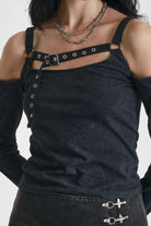Washed black long-sleeve cold-shoulder top with cutout eyelet straps and silver buckles, worn by model