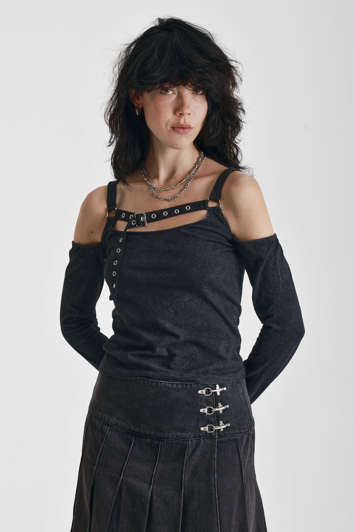 Washed black long-sleeve cold-shoulder top with cutout eyelet straps and silver buckles, worn by model