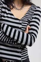 Close up of stud buttons on grey and black stripe asymmetric long sleeve top, worn by a model