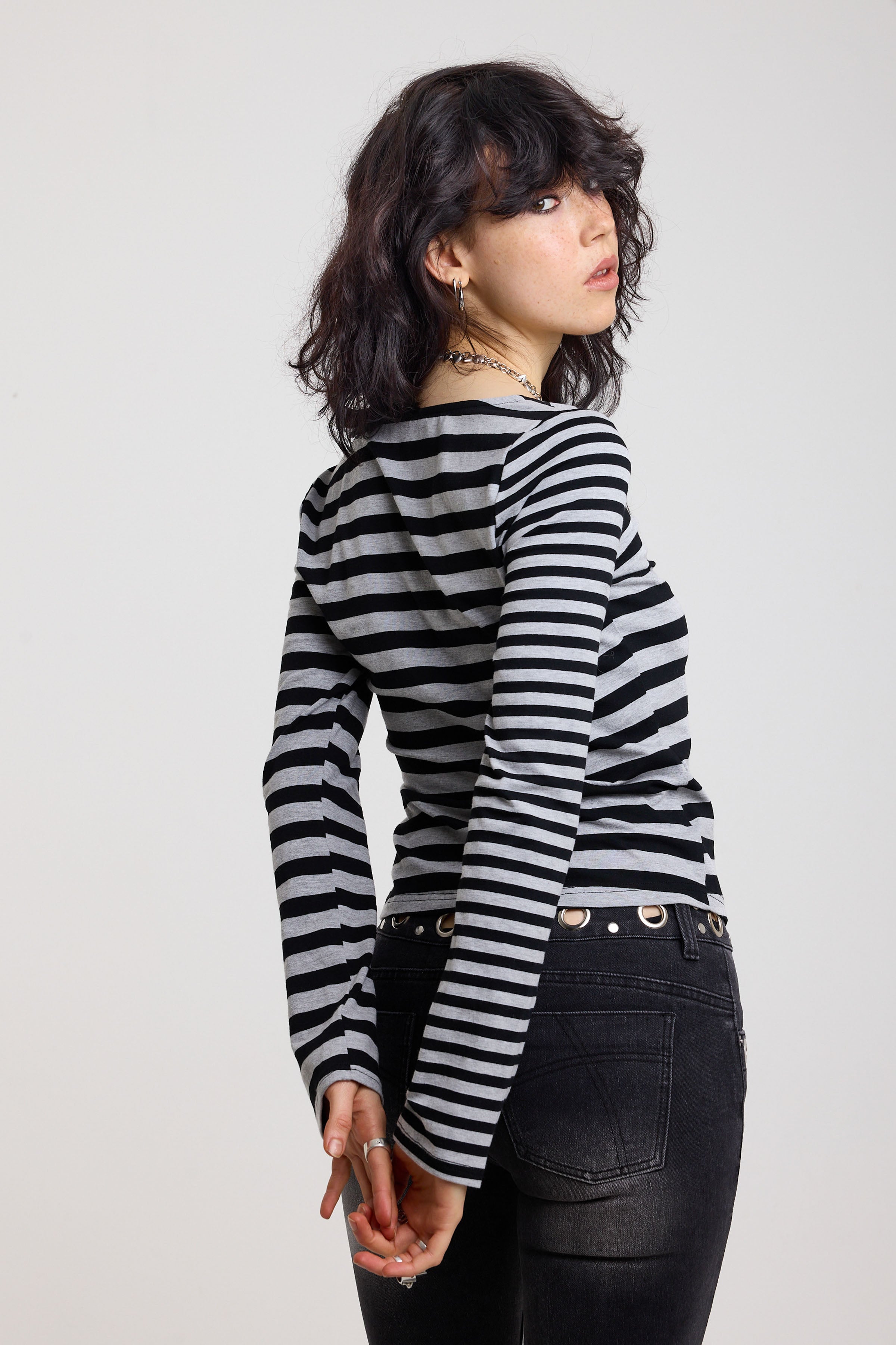 Back image of grey and black stripe asymmetric long sleeve top with stud fastening, worn by a model