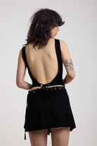 Black slash neck open back tank top with silver eyelet detail, worn by model