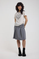 Grey pinstripe pleated midi skirt with eyelet hardware belt and D ring details, worn by model