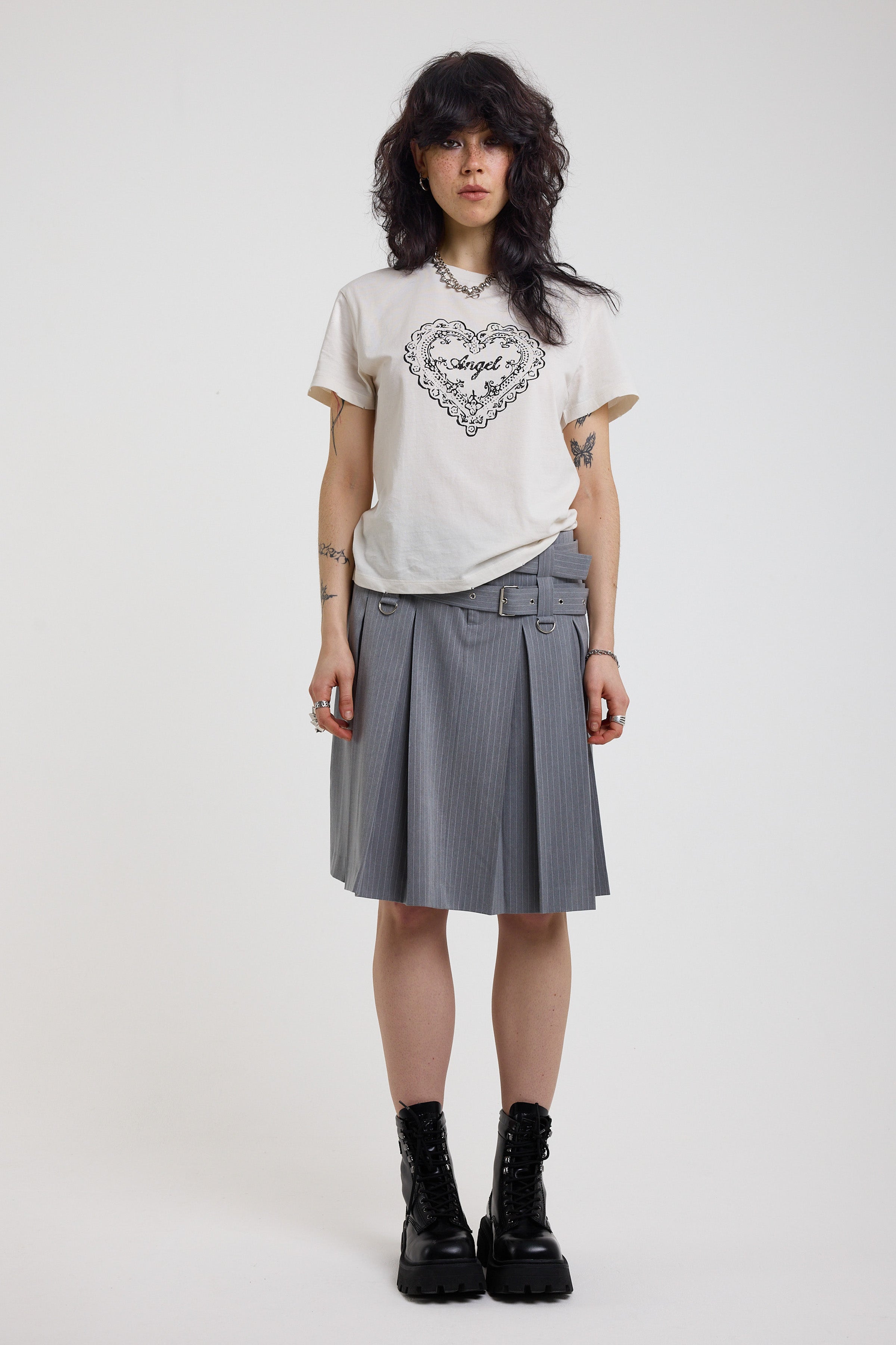 Grey pinstripe pleated midi skirt with eyelet hardware belt and D ring details, worn by model
