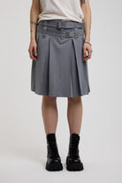 Grey pinstripe pleated midi skirt with eyelet hardware belt and D ring details, worn by model