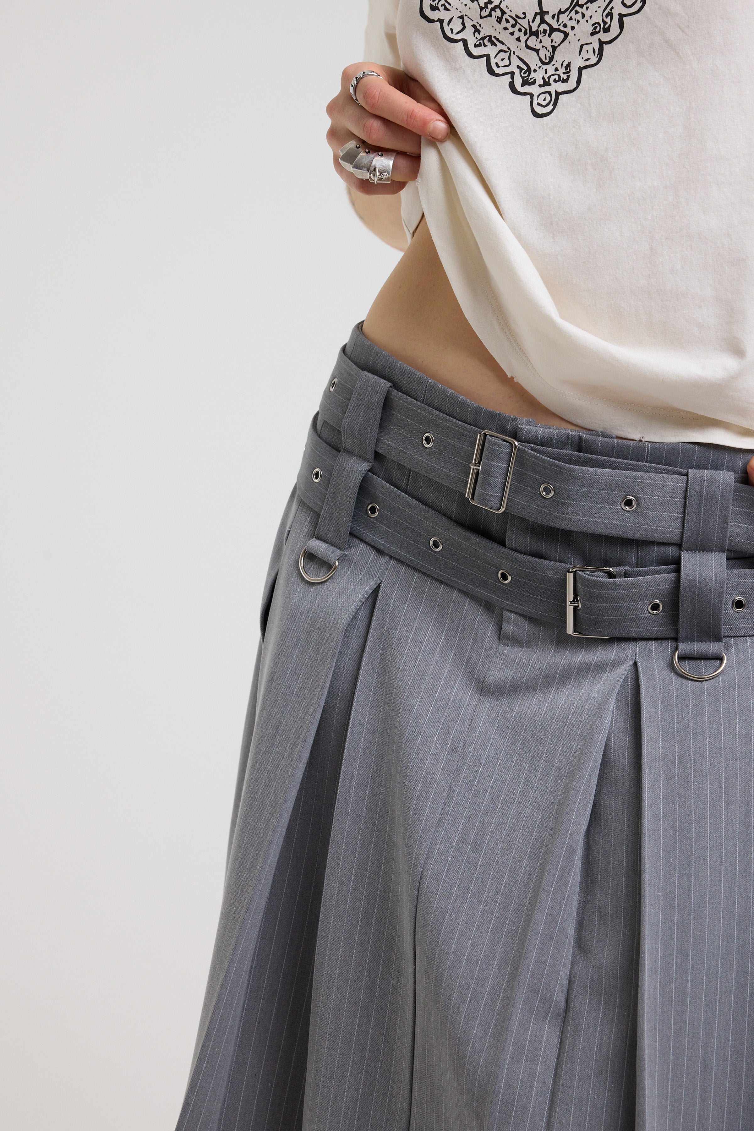 Close up of eyelet detail belt and D rings on grey pinstripe pleated midi skirt