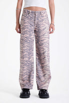 Baggy relaxed leg jeans in all over tiger print, worn by model.