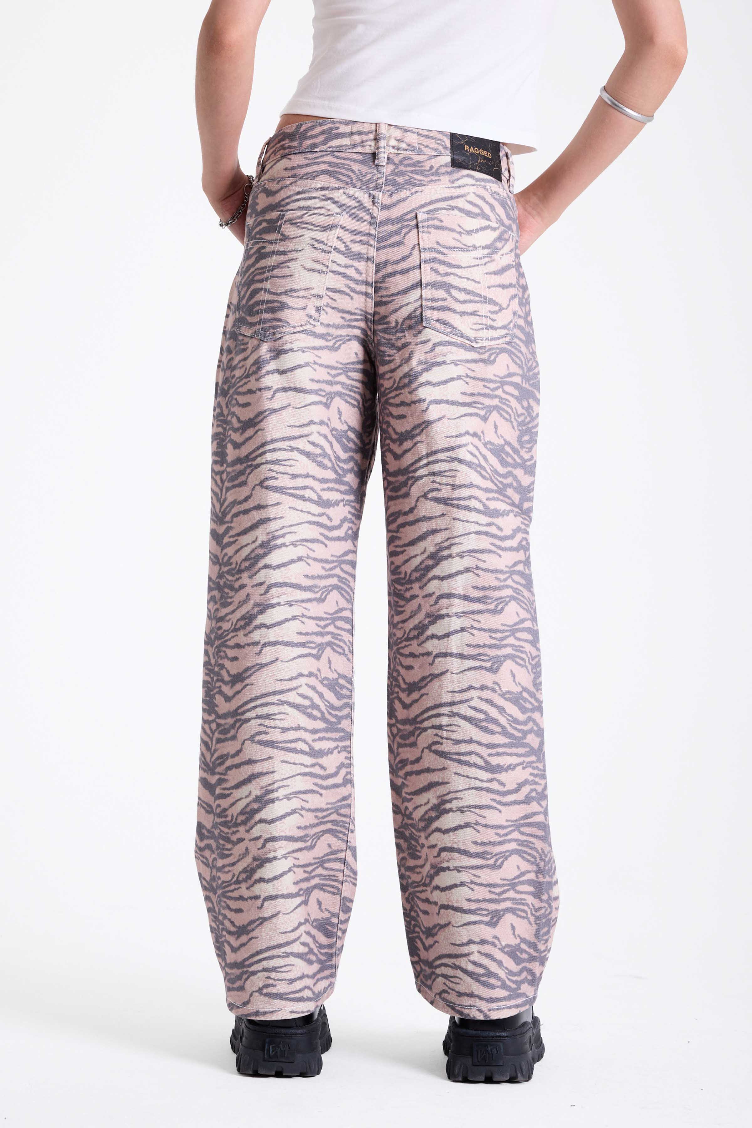 Baggy relaxed leg jeans in all over tiger print, worn by model.