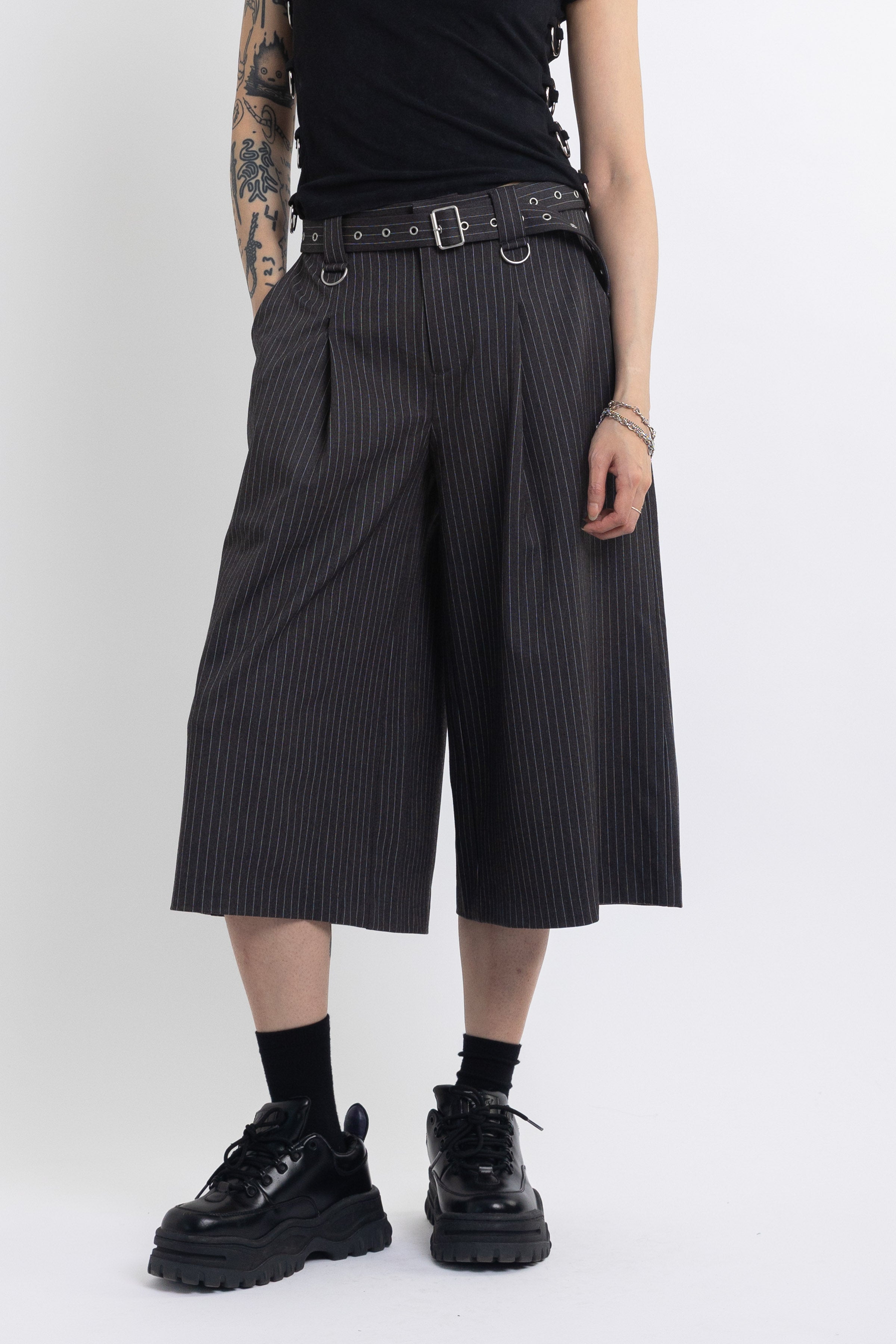 Grey pinstripe longline tailored shorts with eyelet belt and D-ring hardware, worn by model
