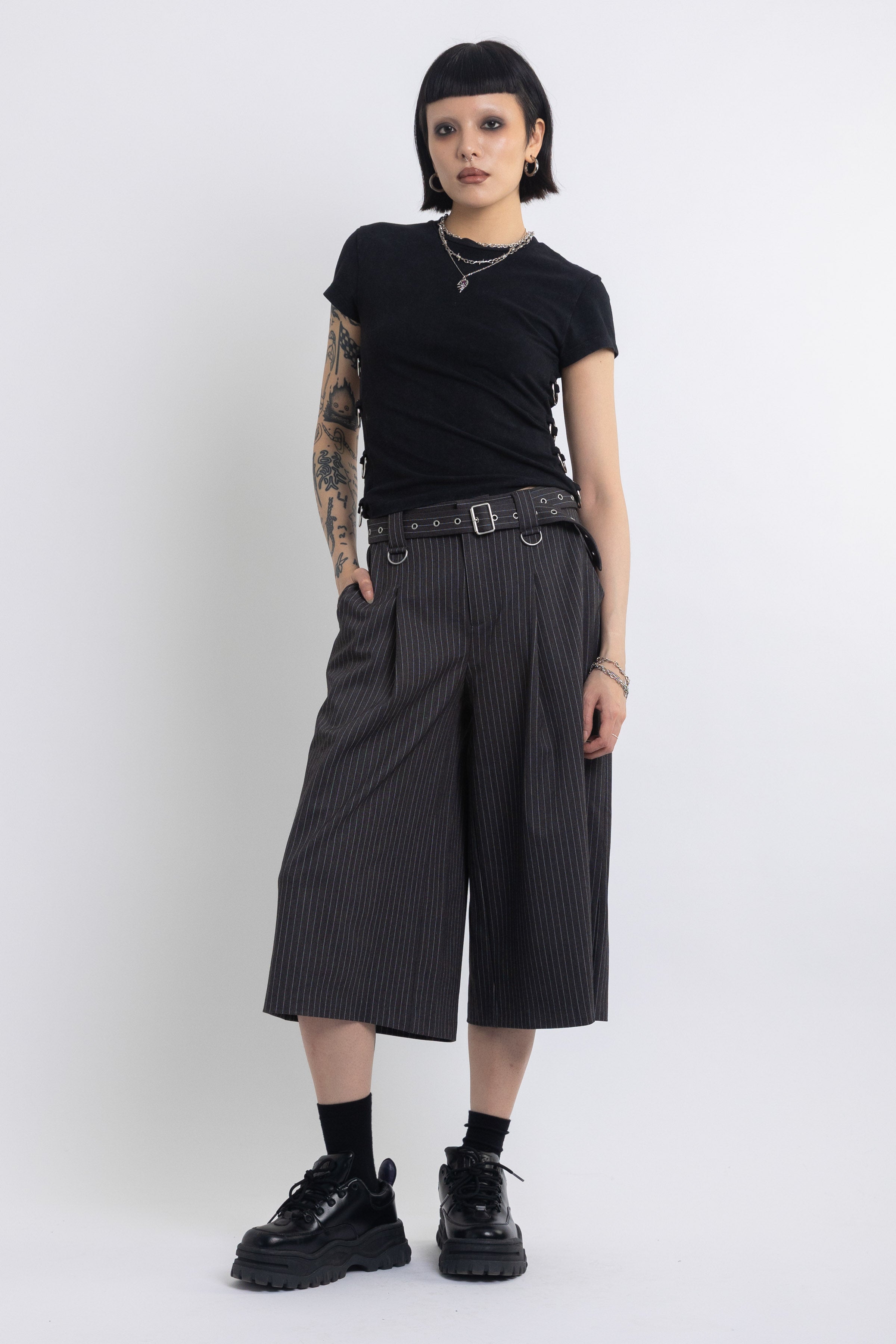 Grey pinstripe longline tailored shorts with eyelet belt and D-ring hardware, worn by model