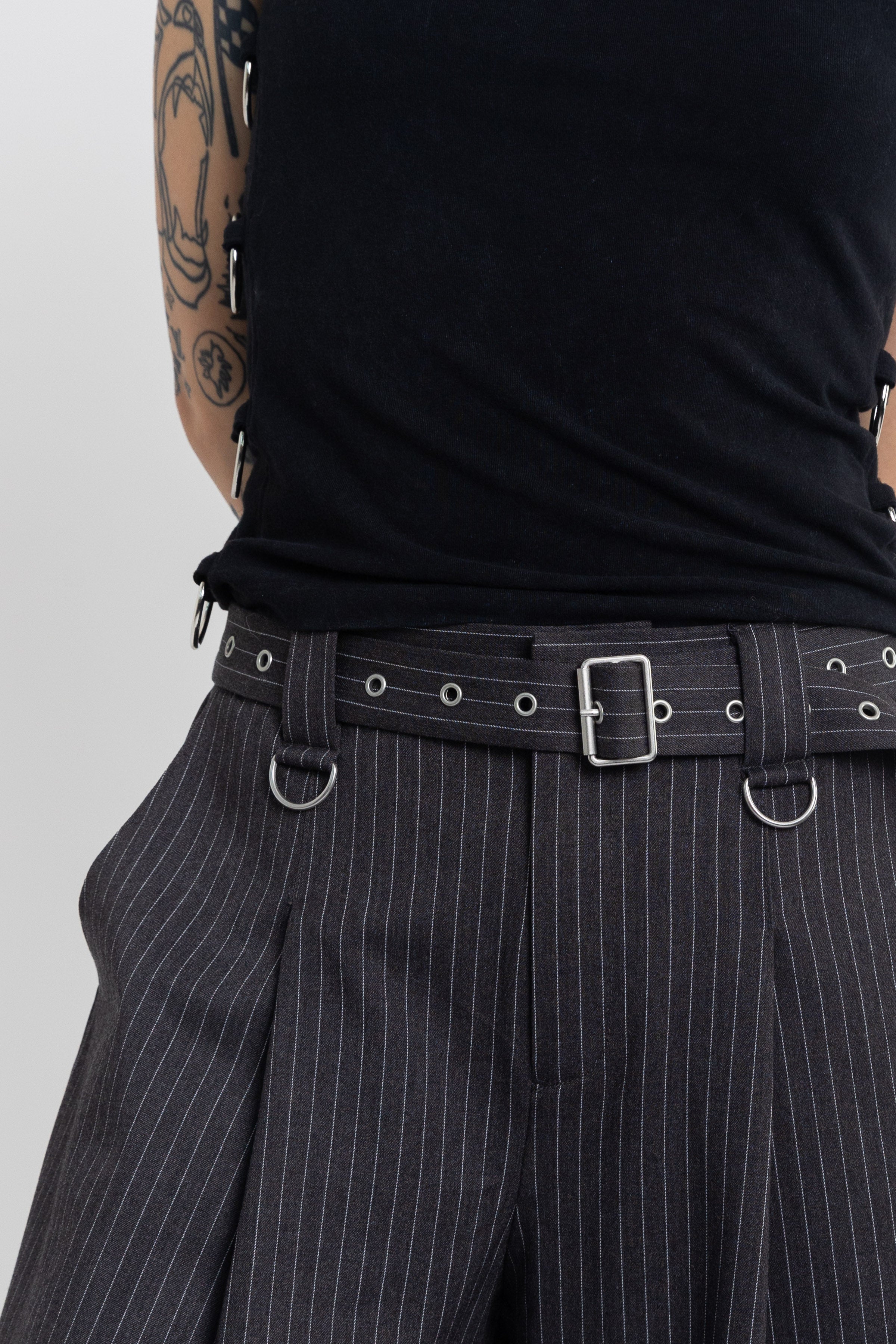 Grey pinstripe longline tailored shorts with eyelet belt and D-ring hardware, worn by model