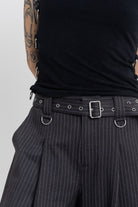 Grey pinstripe longline tailored shorts with eyelet belt and D-ring hardware, worn by model