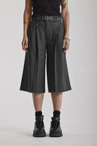 Grey pinstripe longline tailored goliath shorts with silver eyelet belt and D-ring hardware, worn by model