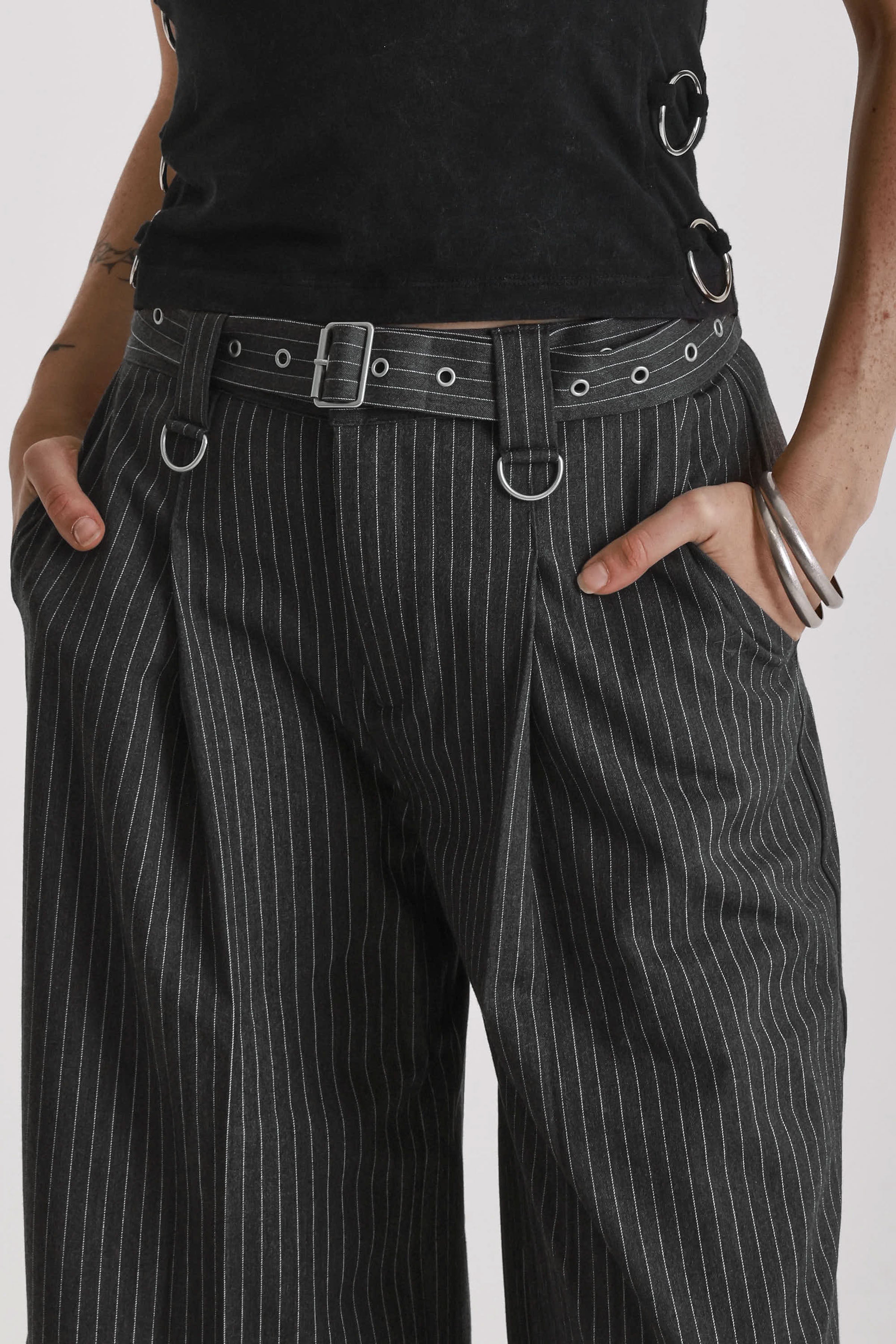Grey pinstripe longline tailored goliath shorts with silver eyelet belt and D-ring hardware, worn by model