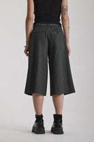 Grey pinstripe longline tailored goliath shorts with silver eyelet belt and D-ring hardware, worn by model