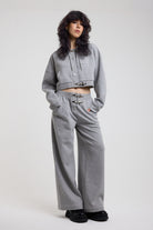 Grey cropped hoodie with silver hardware clasps, worn by model