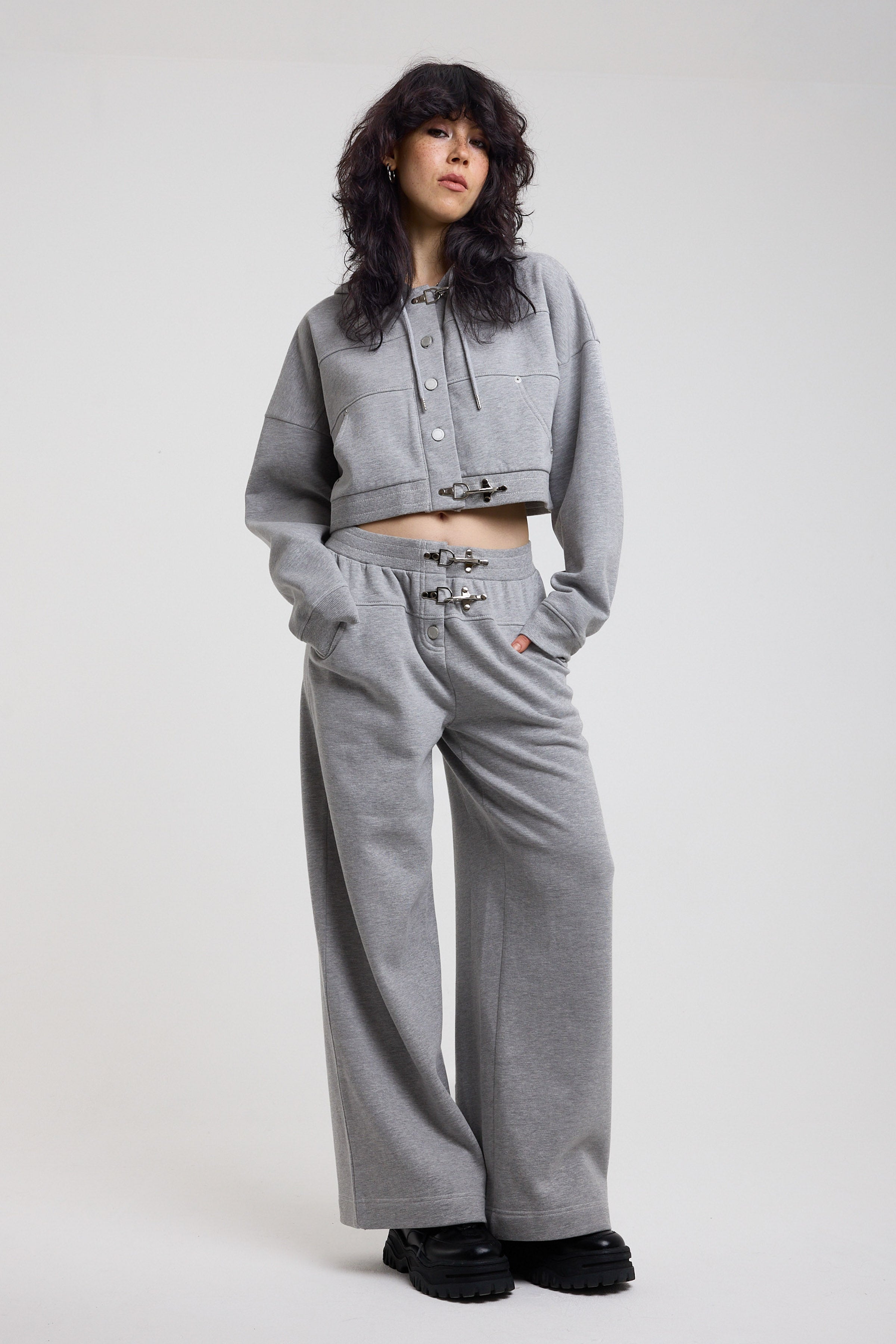 Grey cropped hoodie with silver hardware clasps, worn by model