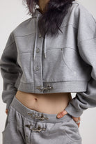 Close up of silver hardware clasps on grey cropped hoodie, worn by model