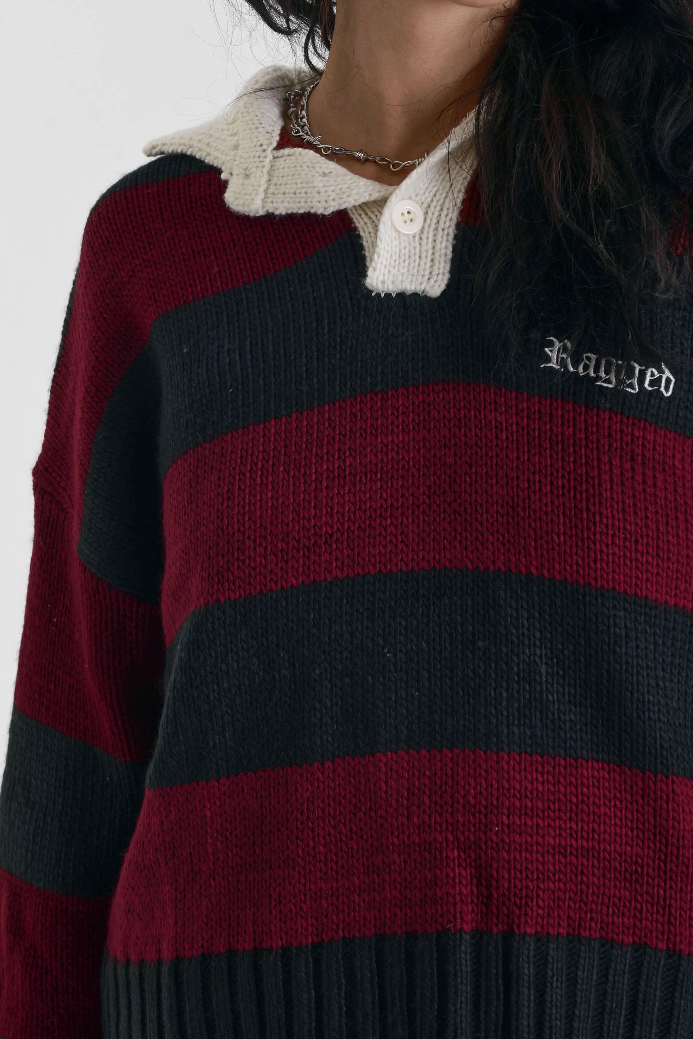 Burgundy and black striped rugby jumper with skull intarsia print, worn by model