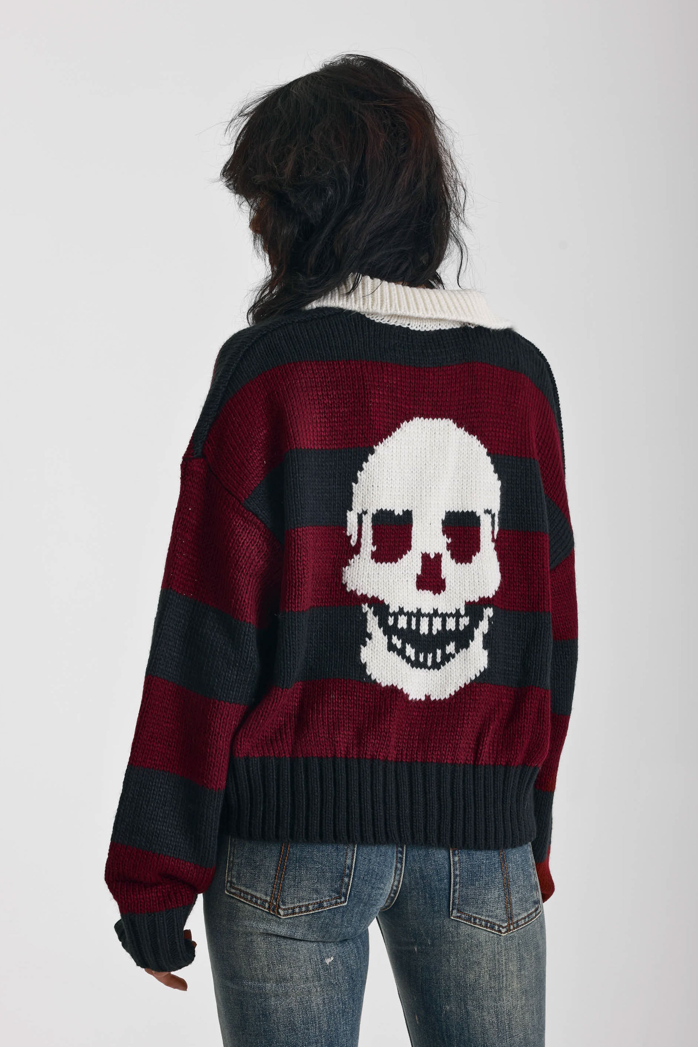 Burgundy and black striped rugby jumper with skull intarsia print, worn by model