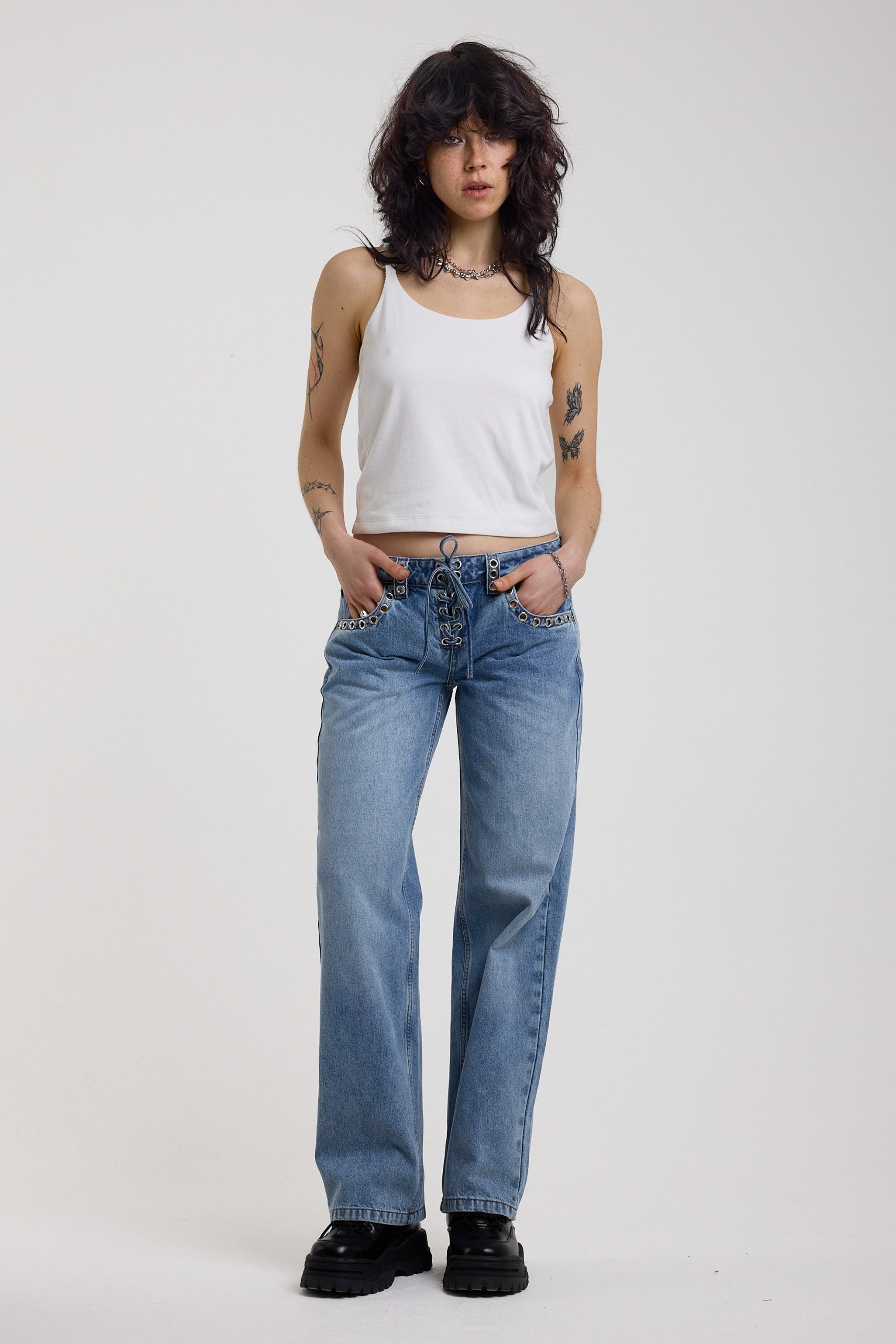 Washed blue denim relaxed straight leg jeans with lace up front and eyelet and rivet hardware, worn by model