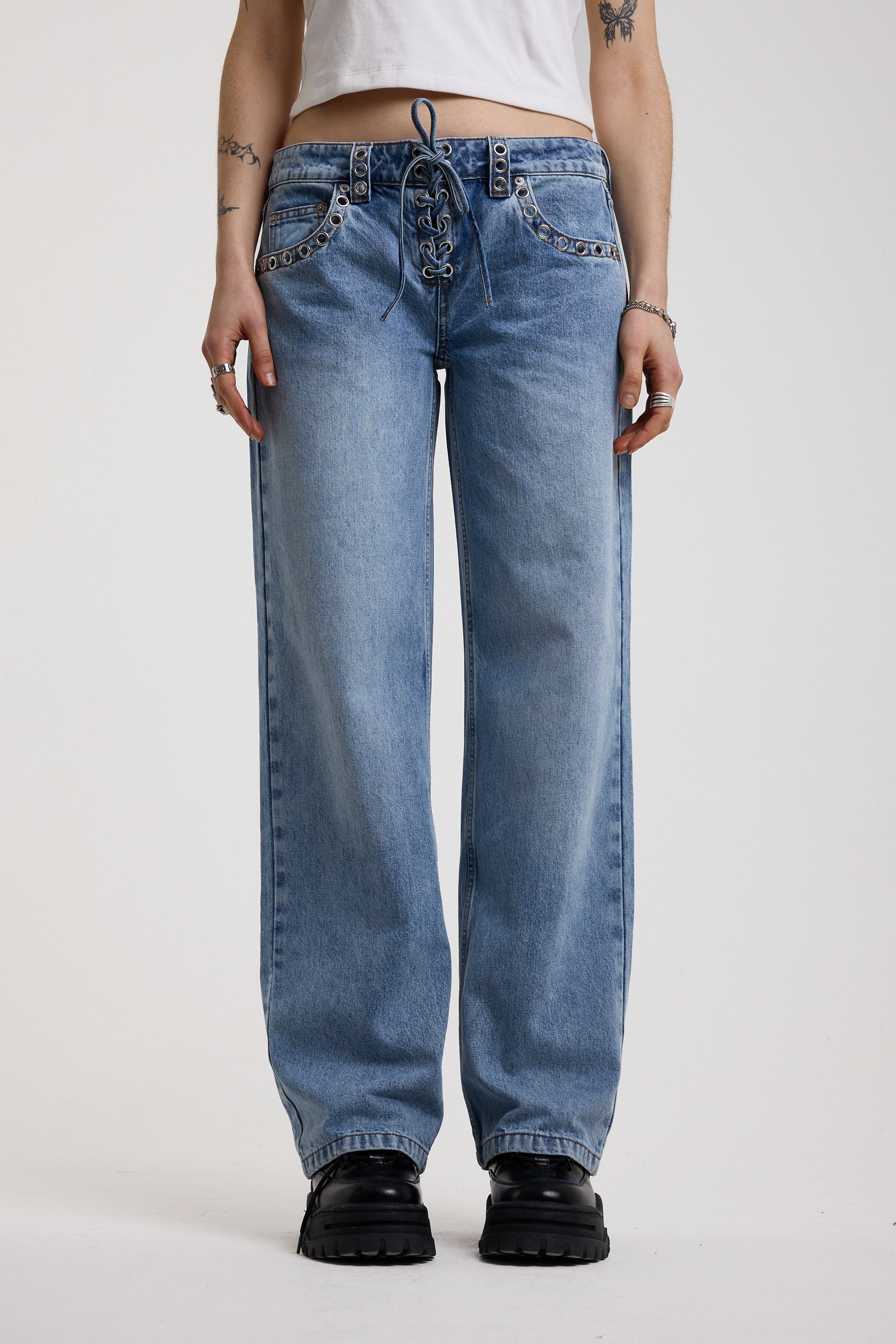 Washed blue denim relaxed straight leg jeans with lace up front and eyelet and rivet hardware, worn by model