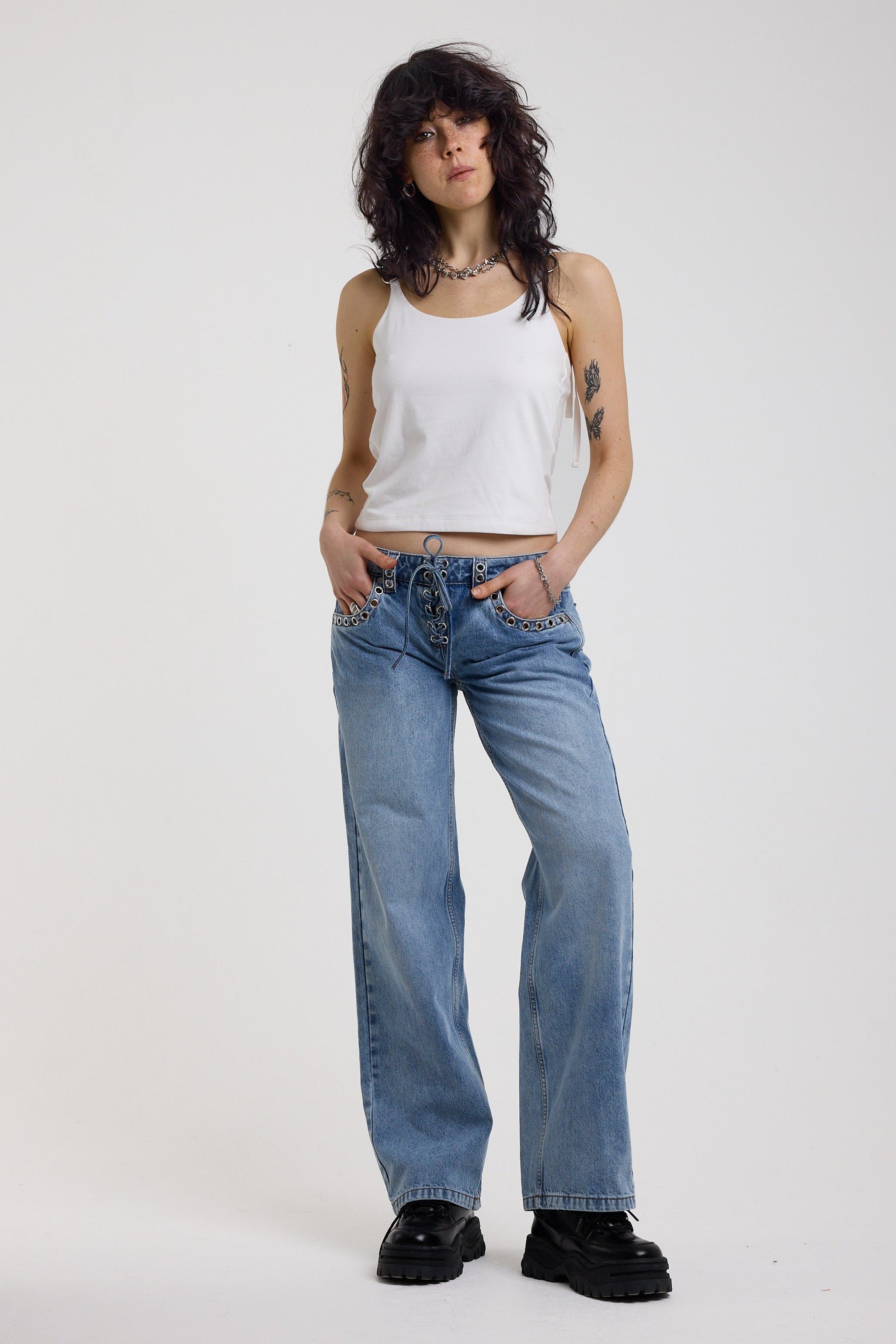 Washed blue denim relaxed straight leg jeans with lace up front and eyelet and rivet hardware, worn by model