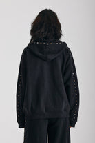 Washed black oversized zip up hoodie with mixed metal stud detail, worn by model
