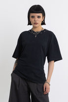 Black oversized t-shirt with open back and eyelet studs, worn by model
