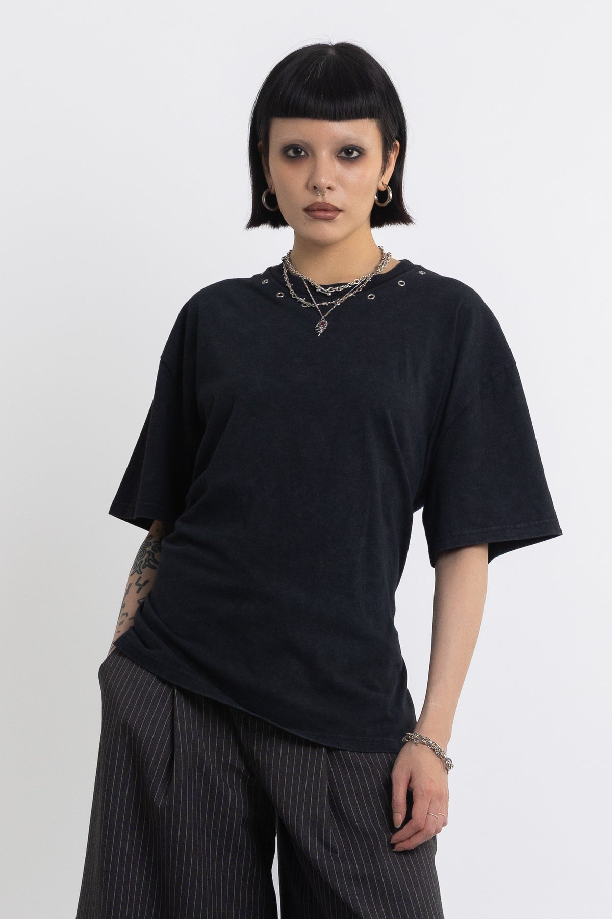 Black oversized t-shirt with open back and eyelet studs, worn by model