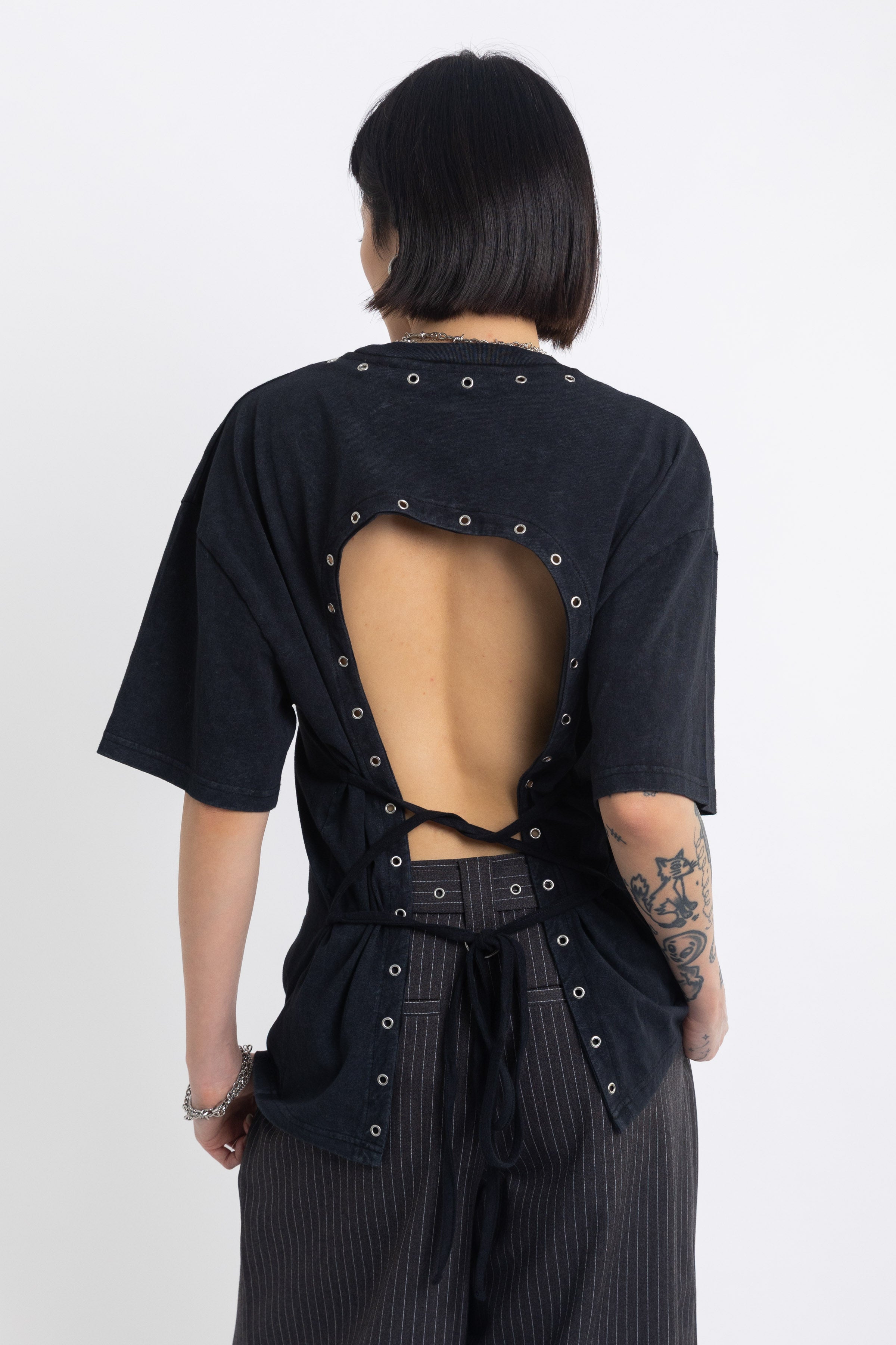 Black oversized t-shirt with open back and eyelet studs, worn by model